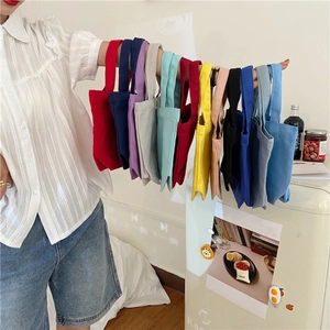 Detailed close-up of colorful canvas mini lunch bags hanging on arm in home setting