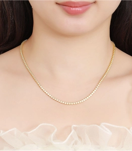 Close-up of golden moissanite tennis necklace worn by a model to show elegant detail