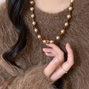 Tiger eye and gold bead necklace shown on a model with a minimalist diamond gold ring