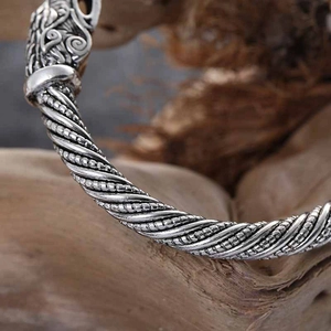 Detailed close-up of a silver viking dragon head on a twisted rope metal cuff bracelet