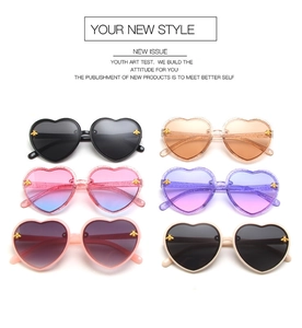 Flat lay of heart-shaped sunglasses with gold bee accents in assorted glitter colors