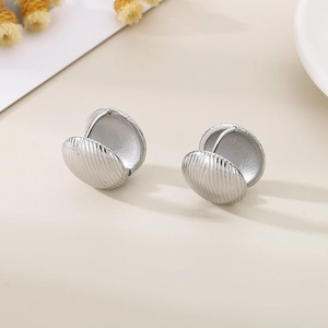 Macro detail of silver shell-shaped titanium earrings with fine vertical ribbed texture