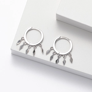 Detail shot of silver hoop earrings with diamond-shaped tassel charms on a white stand
