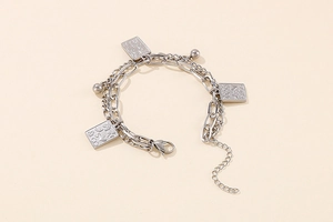 Macro detail of silver double-layer chain bracelet with rectangular poker cards and beads