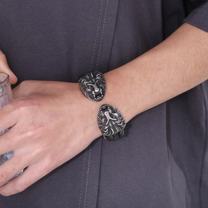 Close-up of men's double lion head open bangle with braided steel cable detail