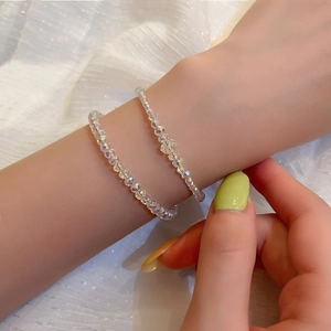 Dettaglio di due braccialetti con perline di cristallo scintillanti su un polso di una donna