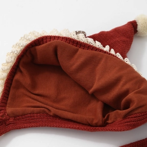 Detail view of red baby knit hat showing soft cotton lining and white lace trim