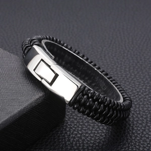 Macro detail of men's black braided leather bracelet with a polished steel clasp