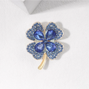 Detailed view of four-leaf clover brooch with blue crystals and gold plated metal base