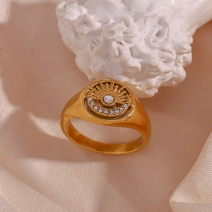 Detail of 18K gold plated eye ring with zircon on beige silk near a statue head