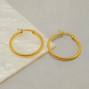 Textured gold stainless steel hoop earrings on marble surface for stylish women
