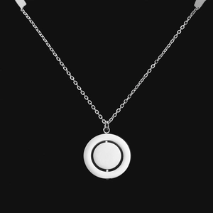 Detailed macro of a stainless steel geometric necklace with a rotatable inner disc pendant