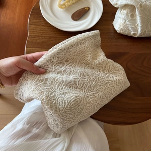 Close-up of the delicate floral lace embroidery and texture on the beige cosmetic bag