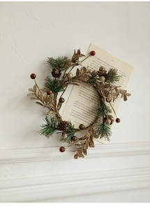 Détail d'une couronne de Noël avec pommes de pin dorées et aiguilles sur fond blanc texturé