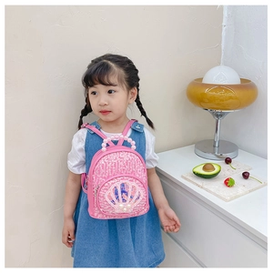 Detailed view of pink sequin shell backpack with pearl handle worn by a young girl