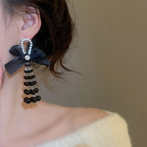 Macro shot of black satin bow earrings with rhinestones and long tassel beads
