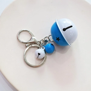 Detail of blue and white baked lacquer cartoon bells with cutout stars on metal keychain
