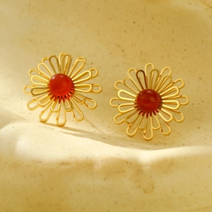 Close-up of gold hollow flower earrings featuring a centered red agate bead