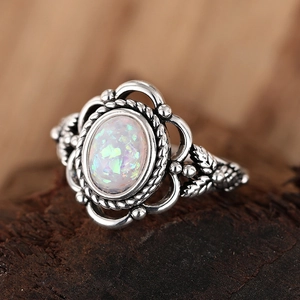 Vintage opal ring with oxidized silver leaf carving on rustic wooden background