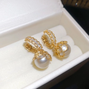 Detailed close-up of gold-plated lace earrings with zircon and large white pearls