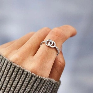 Close-up of interlocking double circle silver ring with inset gems on a hand