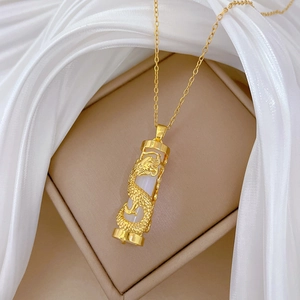 Detailed close-up of golden dragon wrapped around white jade pendant in a beige jewelry box