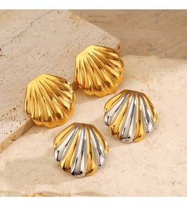 Detail view of two pairs of shell-shaped metal stud earrings in gold and silver on stone