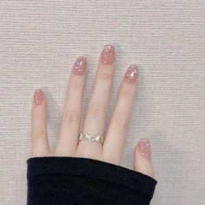 Detail of pink press-on nails with silver glitter stars, pearls and a gold heart ring