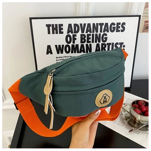 Detail of canvas chest bag featuring contrast colors with green body and orange strap