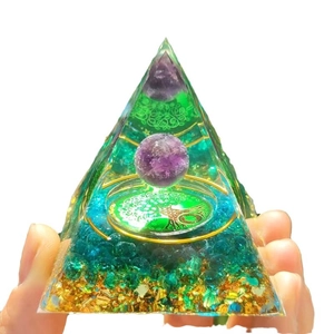 Orgone energy pyramid with amethyst sphere, tree of life, and blue gravel on white backdrop