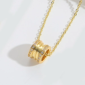 Macro detail of gold spiral cylinder pendant with tiny zircon stones on an O-chain