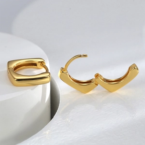 French style square geometric gold metal hoop earrings displayed on white stone platform
