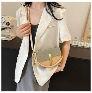 Detail of beige color-block saddle bag featuring a gold metal clasp and chain strap