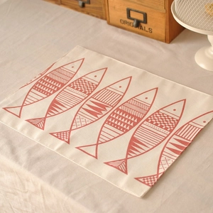 Close-up of linen table napkin with red fish pattern and neat edge stitching details