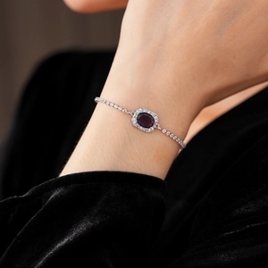 Close-up of elegant purple gemstone bracelet with silver chain on model's wrist