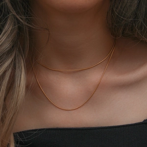 Close-up of golden stainless steel snake chain necklace showing fine metallic texture on neck