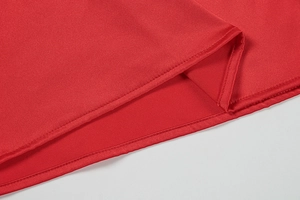 Detail shot of the hemline stitching and red satin fabric of the sexy evening dress