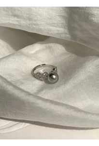 Close-up of a silver ring featuring a large grey pearl and sparkling zircon accents