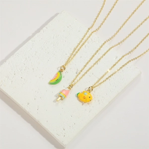 Three gold necklaces with enamel watermelon, ice cream, and fish charms on stone