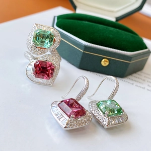 Macro shot of silver jewelry set featuring emerald-cut pink and green gemstones with diamonds