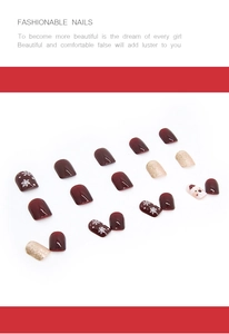 Détail macro de faux ongles de Noël rouge vin avec motifs de flocons et de rennes