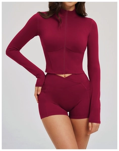 Detail view of burgundy yoga top with full zipper, stand collar and thumbhole cuffs