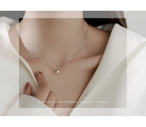 Detail shot of a minimalist S925 sterling silver cube pendant on a delicate box chain