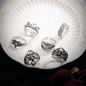 6-piece silver gothic skull ring set with crown and feather details on a vintage tray