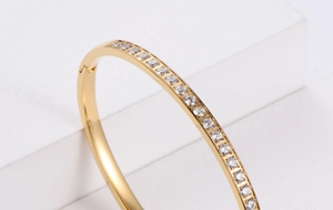 Detailed view of the gold hinge closure and sparkling row of rhinestones on the bangle