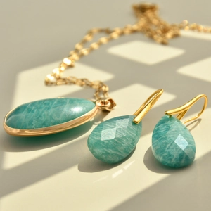 Macro detail of teardrop green stone necklace and faceted earrings in gold setting