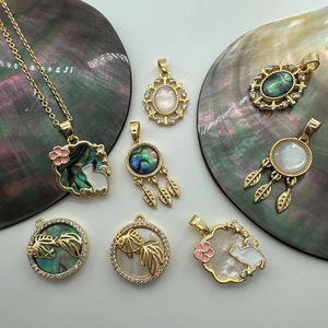 Macro detail of 18K gold-plated shell cat and fish pendants for DIY jewelry making