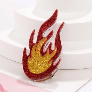 Acrylic flame brooch with red and yellow glitter finish on a white display stand