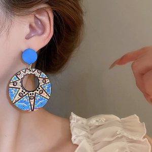 Macro side view of large circular artistic sunflower earrings worn by a female model