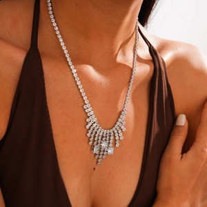Detailed view of silver geometric tassel necklace with cubic zirconia on model's neck